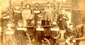 Picture of 10 Uffculme men with face masks and name boards. Something to do with William Furze's business?
